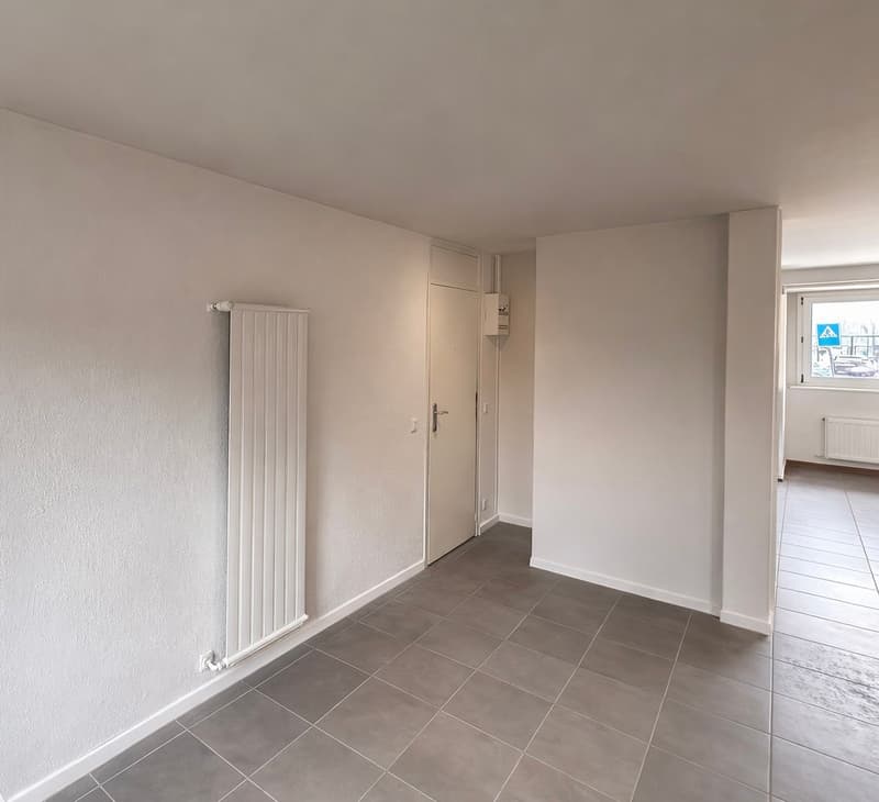 Empty room with white walls, white floor, and white radiator