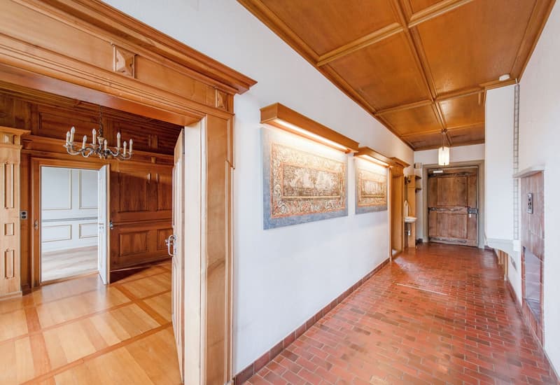 wooden floor, wooden ceiling, chandelier, two paintings on the wall, wooden doors