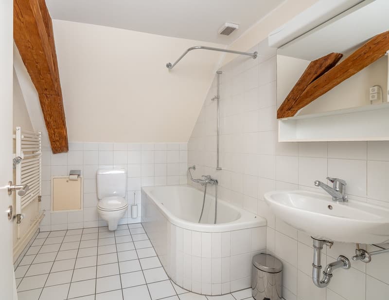white tiled floor, white bathtub, white sink, white toilet, wooden beams