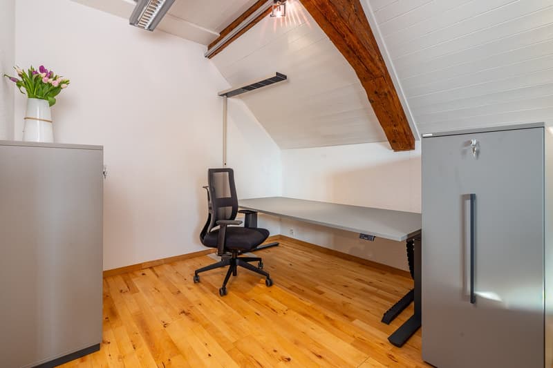 wooden floor, white walls, office chair, desk, white vase with flowers, gray cabinets