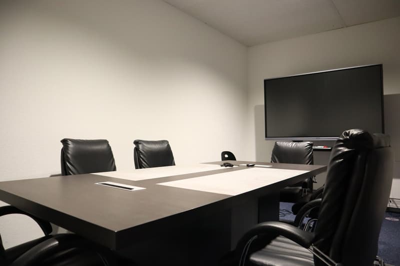 conference room with a large table, black leather chairs, flat screen TV mounted on the wall