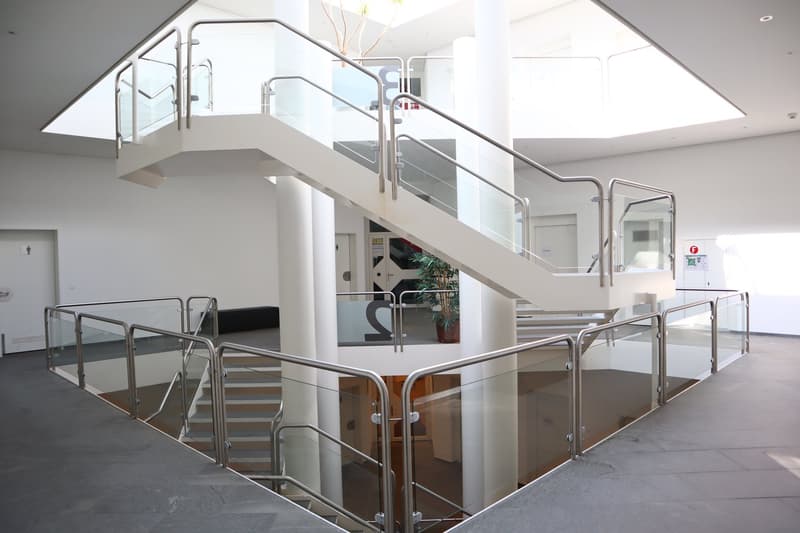 modern building, glass railings, white walls, gray floor, central staircase