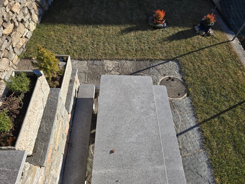 Stone wall, grass, concrete bench, 2 potted plants, 1 solar light