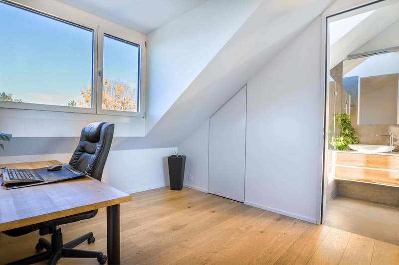 modern office with desk, leather chair, wooden floor, large windows, bathroom visible