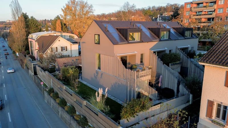 Modern house, grey walls, brown roof, solar panels, balconies, stairs connecting floors, garden, car park