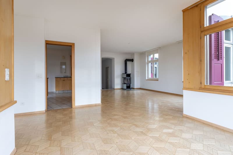 Empty room with wooden floor, white walls, fireplace, door, window