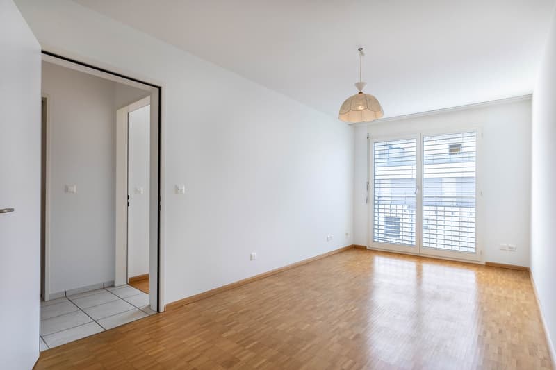 empty room, wooden floor, white walls, sliding glass doors to balcony, ceiling lamp