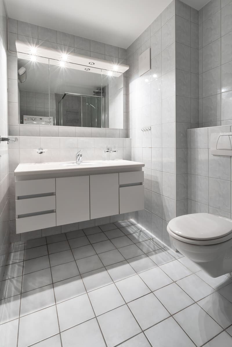 white tiles, white sink, white toilet, large mirror, shower area