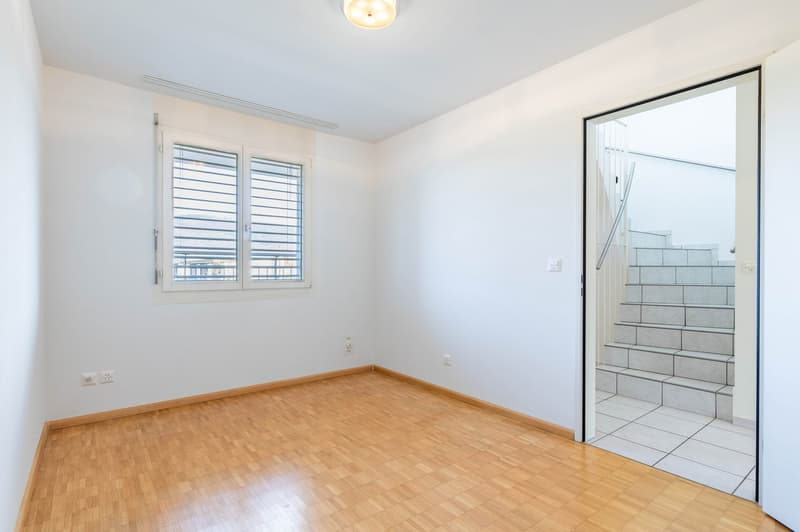 empty room, wooden floor, white walls, window with blinds, power outlets, open door to stairs