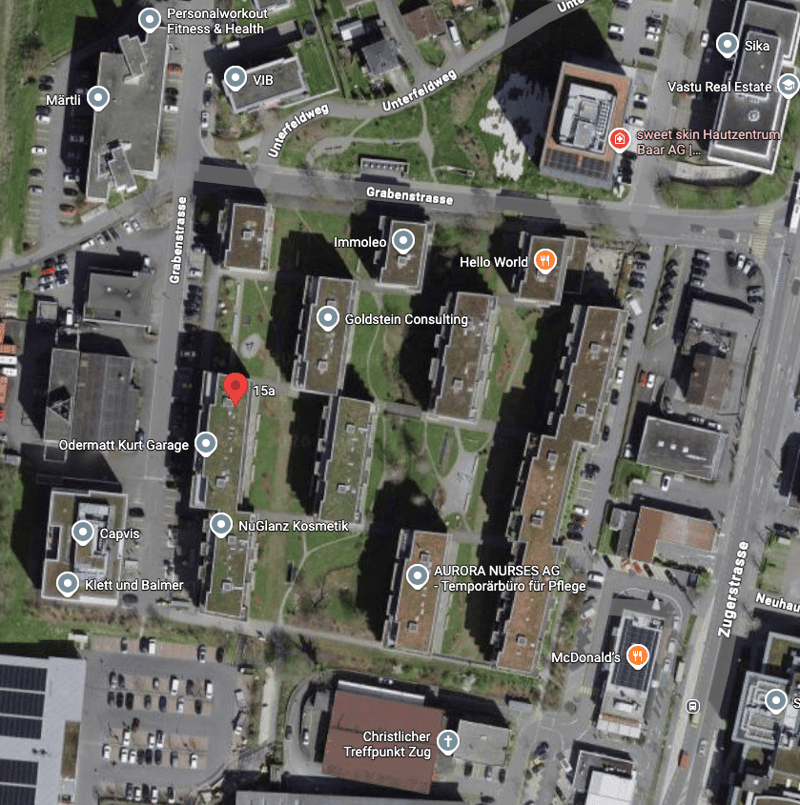Aerial view of a neighborhood with various buildings, roads, and parking lots. Notable landmarks include Personalworkout Fitness & Health, VIB, sweet skin Hautzentrum Baar AG, and McDonald's.