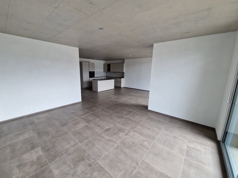 Empty room with white walls, gray tiles, kitchen island, and cabinets