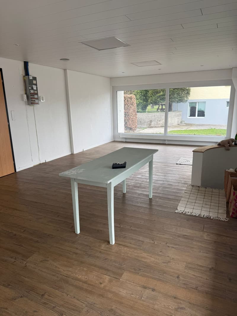 empty room, wooden floor, white table, large windows, view of outside