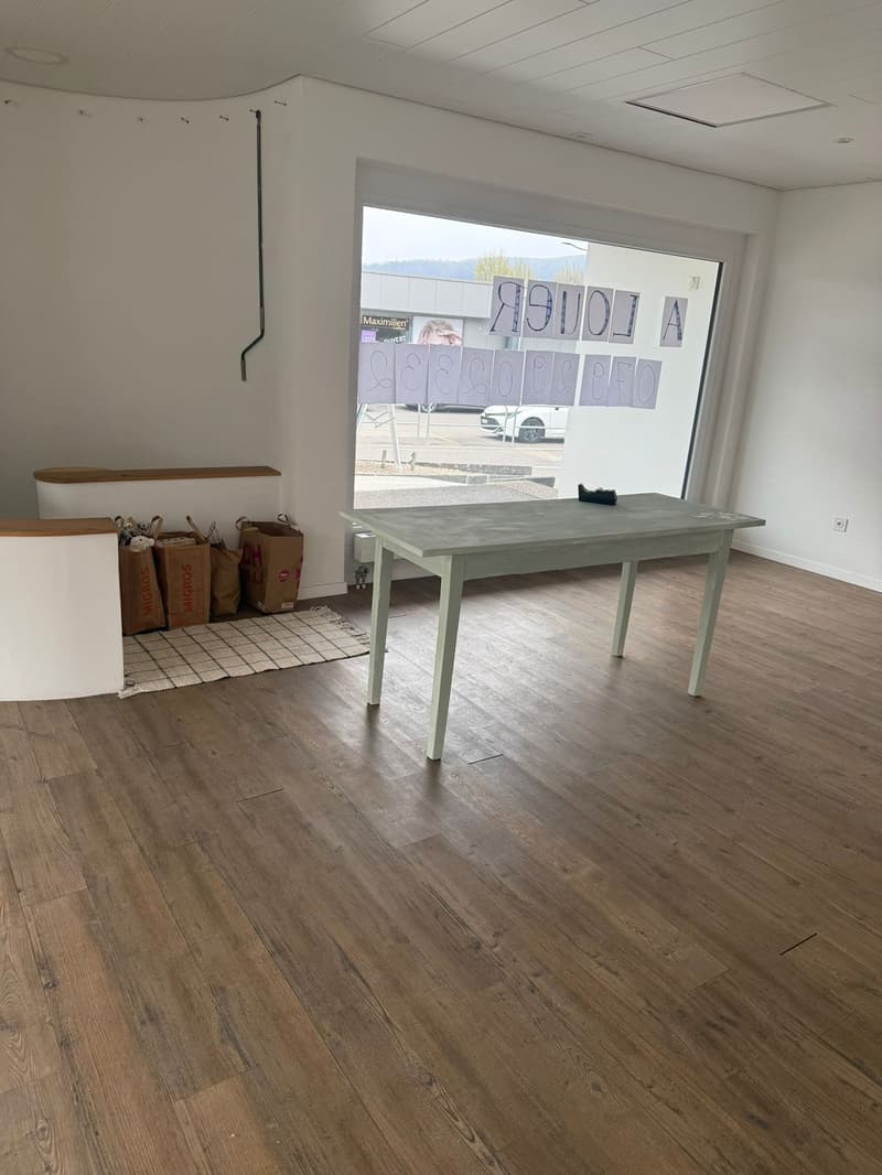 empty room, wooden floor, large window, table, bags, rug