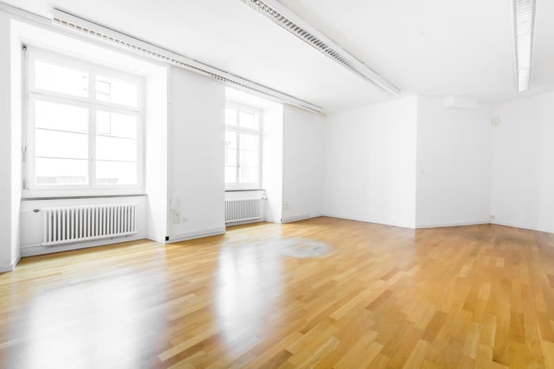empty room, wooden floor, white walls, two windows, radiators