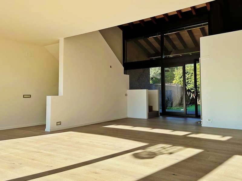 Empty room with wooden floor, white walls, large glass doors leading to a balcony, and a staircase