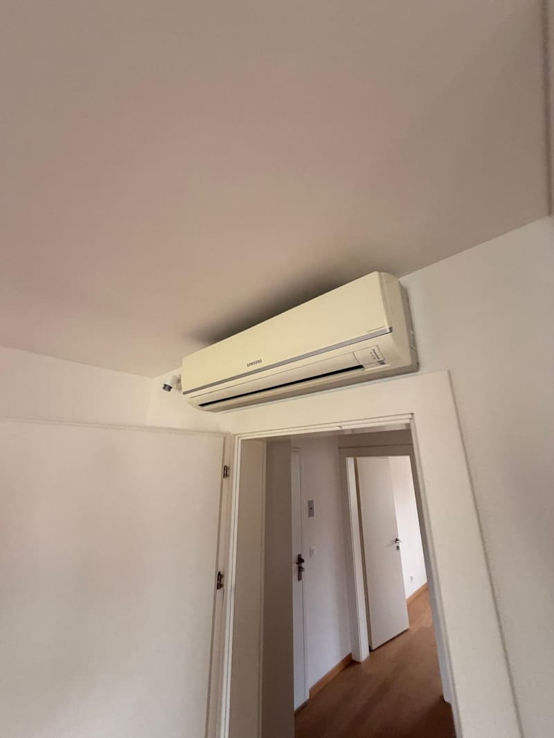 white walls, white ceiling, white door, wooden floor, air conditioner mounted on the wall