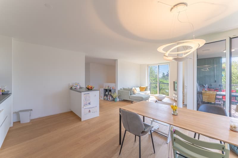 Dining area with wooden table, chairs, and a balcony with a view of the outside