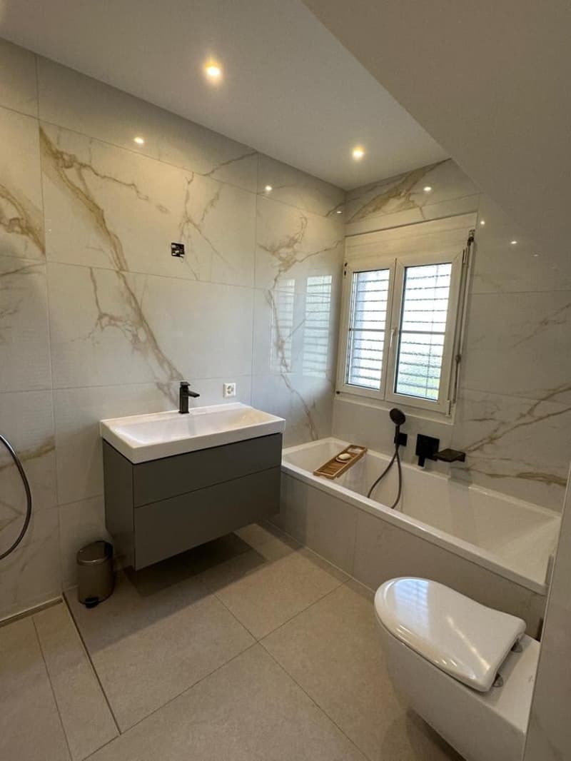 White tiles, bathtub, shower, toilet, sink, built-in cabinet, white marbled walls, glass window, outlets