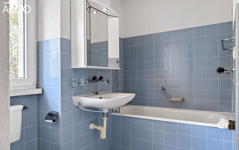 Bathroom with blue tiles, white sink, white bathtub, white toilet, silver towel rack