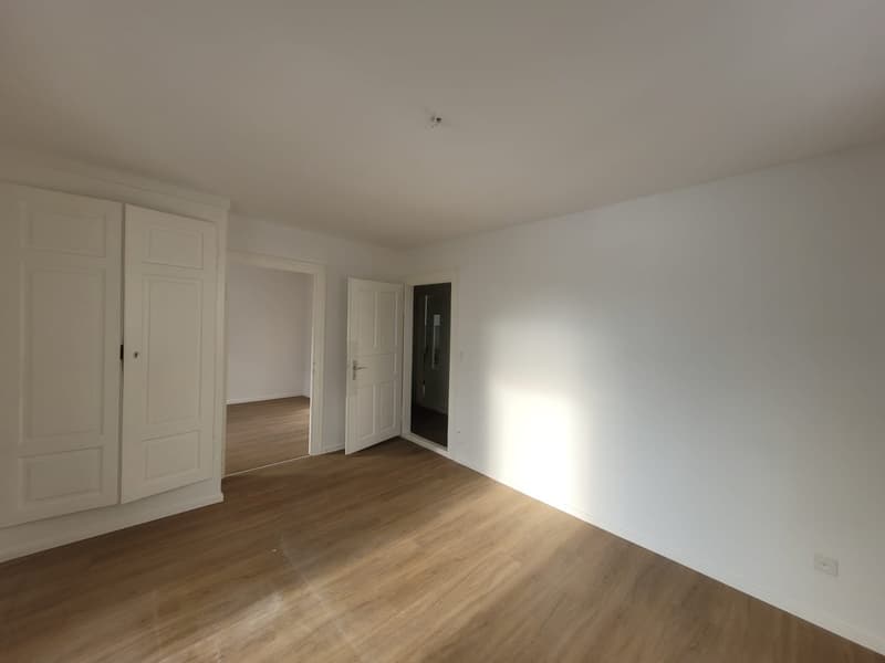 Empty room with white walls and wooden floors, three doors