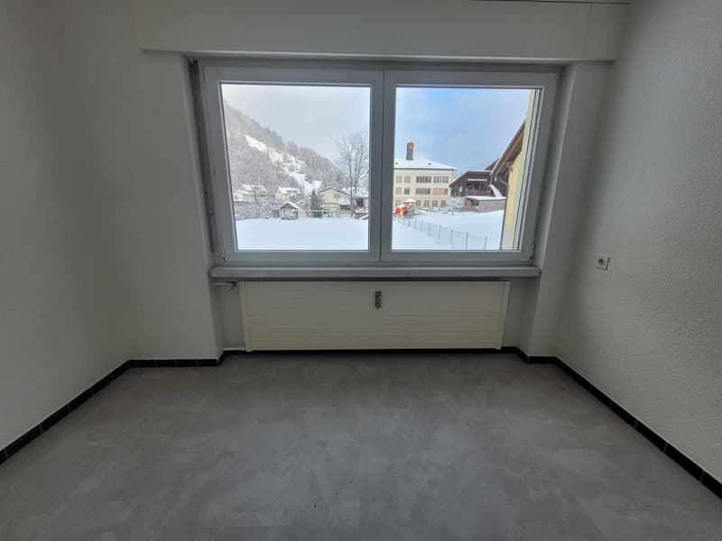 empty room with gray floors, large window, white walls