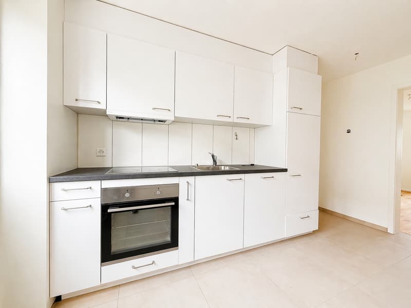 modern kitchen with white cabinets, black countertops, stainless steel appliances, tiled floor