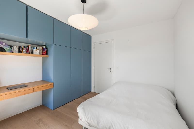 Chambre 2 / a small bedroom in an apartment with a white wall, blue cabinets and a bed