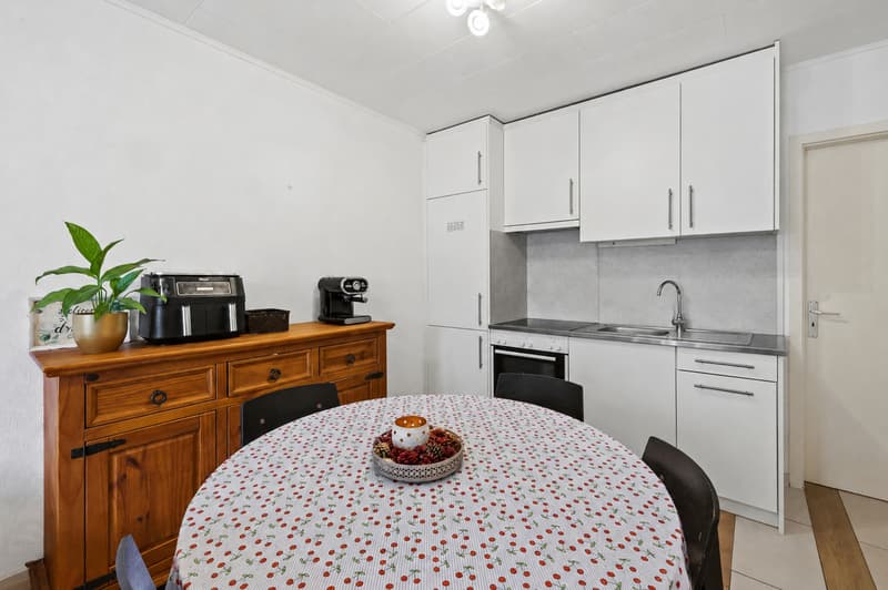Espace repas et cuisine ouverte / a small room with a white kitchen and a red and white table and chairs