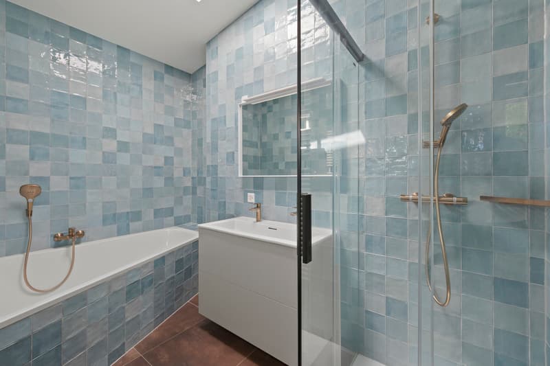 Salle de bains / a bathroom with blue tiles on the walls and a white sink