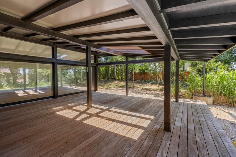 Terrasse extérieure couverte / a large room with wooden floors and a covered deck