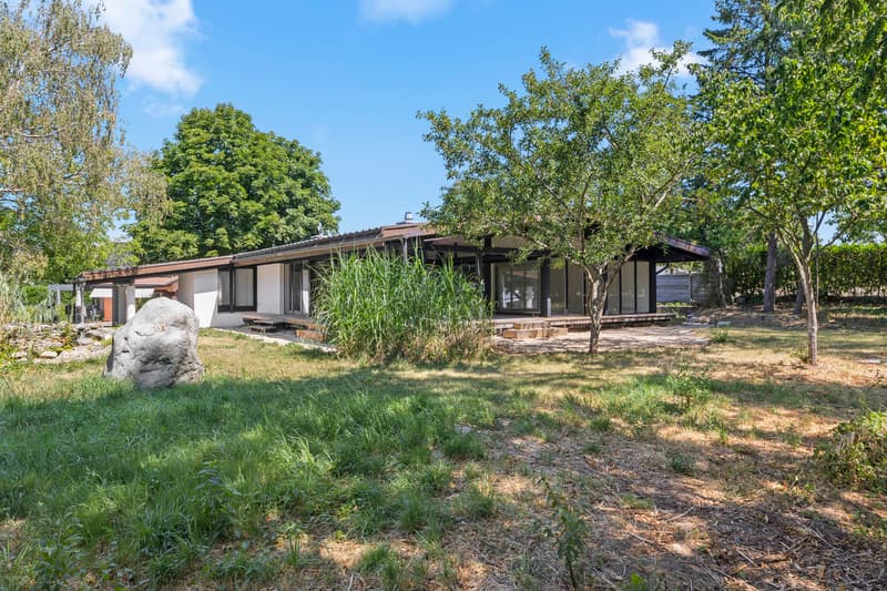 Villa dans un environnement verdoyant / a large rock in front of a home with trees