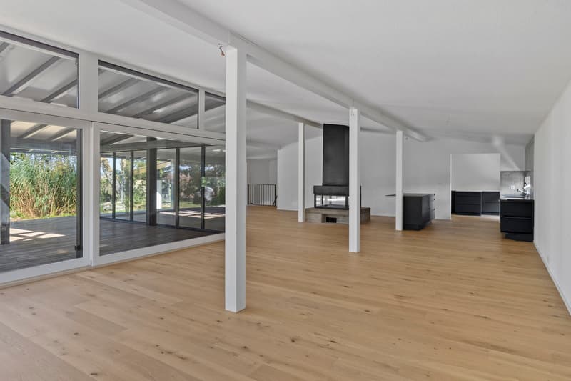 / an empty room with wooden floors and large windows opens up into a home