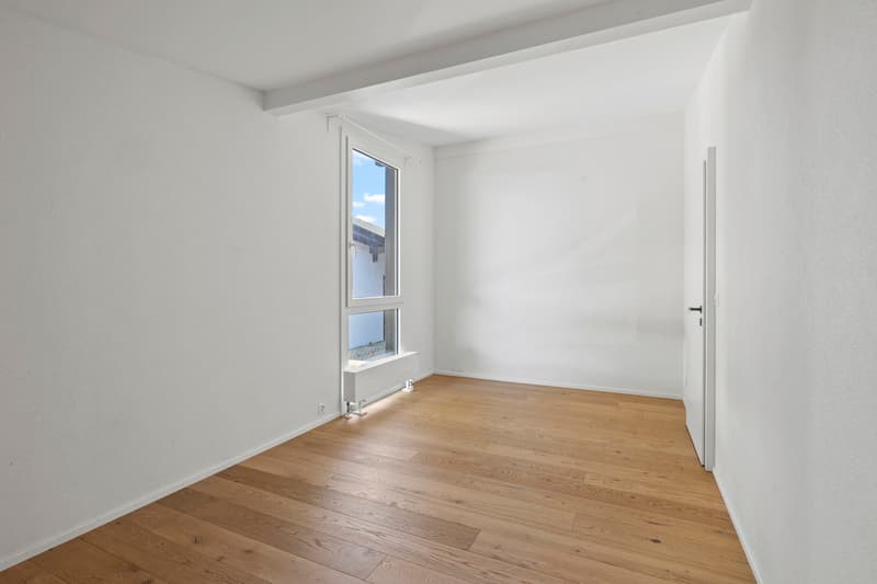Chambre / an empty room with white walls and wooden floors and a large window