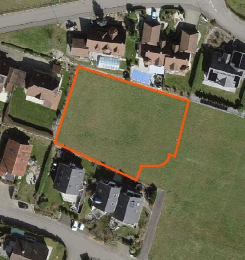 Plot of land with an area of 1,000 square meters, surrounded by houses and greenery.