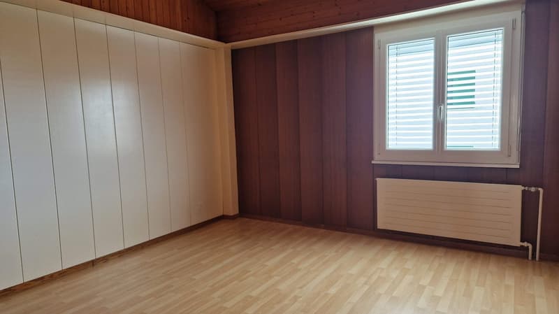 empty room with wooden floor, white and brown wooden walls, large closet, window with shutters