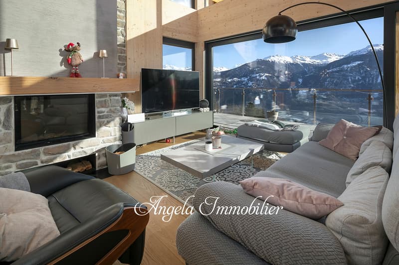Spacious living room with large windows offering a panoramic view of the snowy mountains, wooden walls and floors, modern furniture including a sofa, coffee table, and TV stand, decorative elements like lamps and figurines
