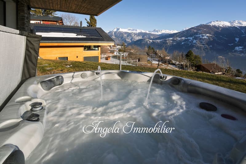 Luxury chalet with a hot tub on the balcony, overlooking a snowy mountain landscape