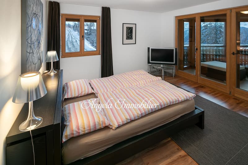 double bed, two pillows, two lamps, TV, picture frame, wooden floor, sliding glass doors, balcony, view