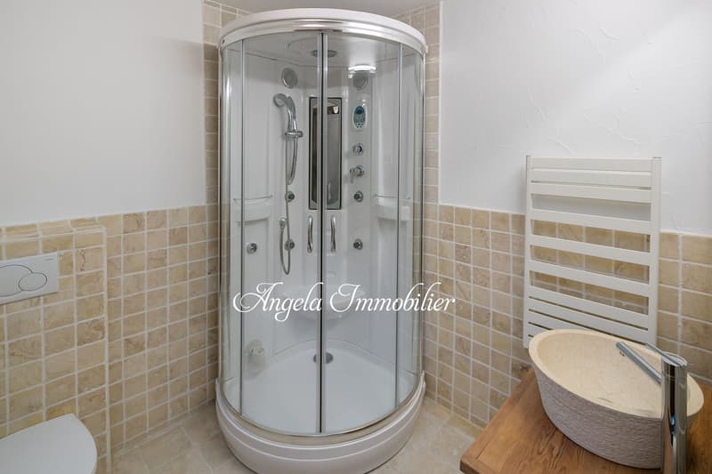 Modern bathroom with a glass walk-in shower, a wooden countertop, a white sink, and a white towel rack.