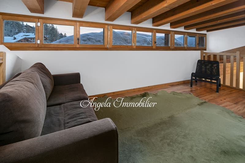wooden ceiling, large windows, brown sofa, wooden floor, green rug, black chair