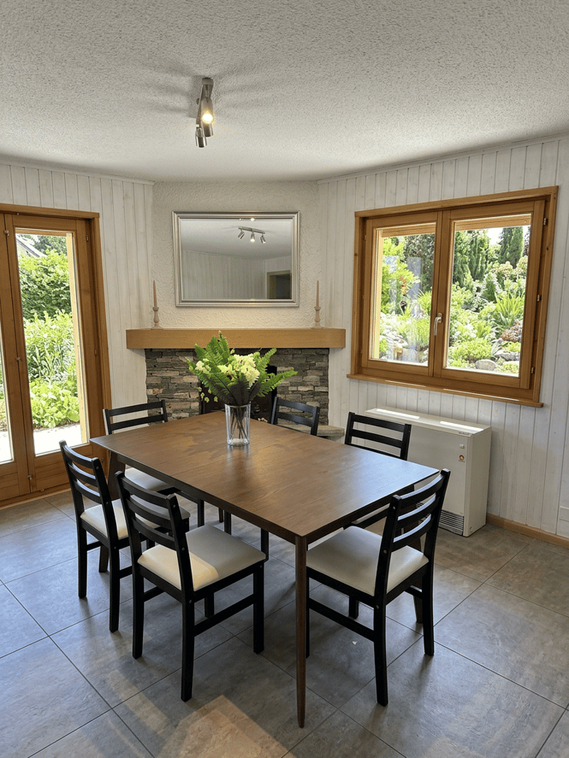 Dining room with wooden table, chairs, fireplace, and windows