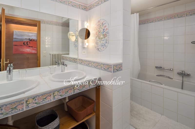 bathroom with double sink, bathtub, mirror, shower curtain, wall tile design, radiator