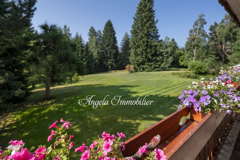balcony with flowers, large green lawn, trees, clear sky
