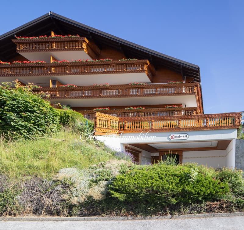 3 story house, wooden exterior, multiple balconies, red flowers on balconies, green lawn