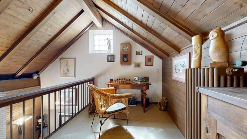 spacious attic with a vintage wooden chair, a chess board on a desk, and a wooden ceiling