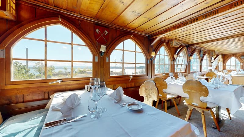 wooden interior, arched windows, white linen tablecloths, wine glasses on table, outdoor view