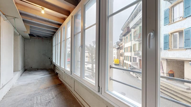 Empty room, wooden ceiling, concrete floor, large windows, balcony with railings