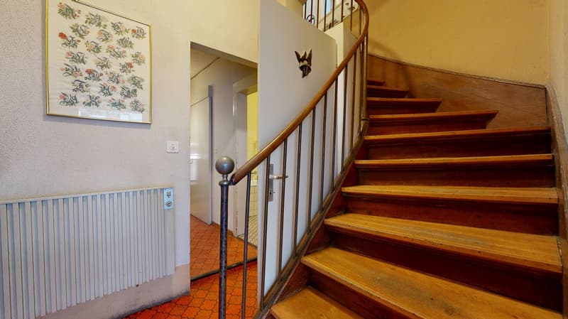 Radiator on wall, tiled floor, white painted walls, spiral staircase, hallway