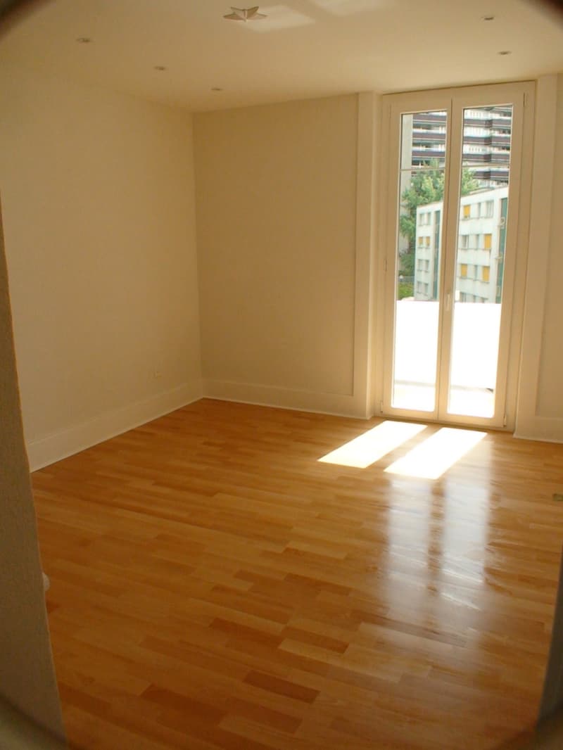 empty room, wooden floor, white walls, sliding glass doors leading to balcony