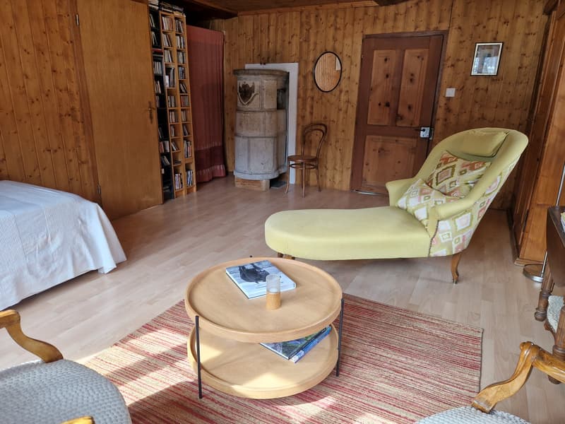 wooden walls, wooden floor, bed, chair, table, books, mirror, fireplace